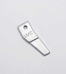 Small silver metal blade-shaped tool with a circular hole near the top and 'LMC' engraved on it